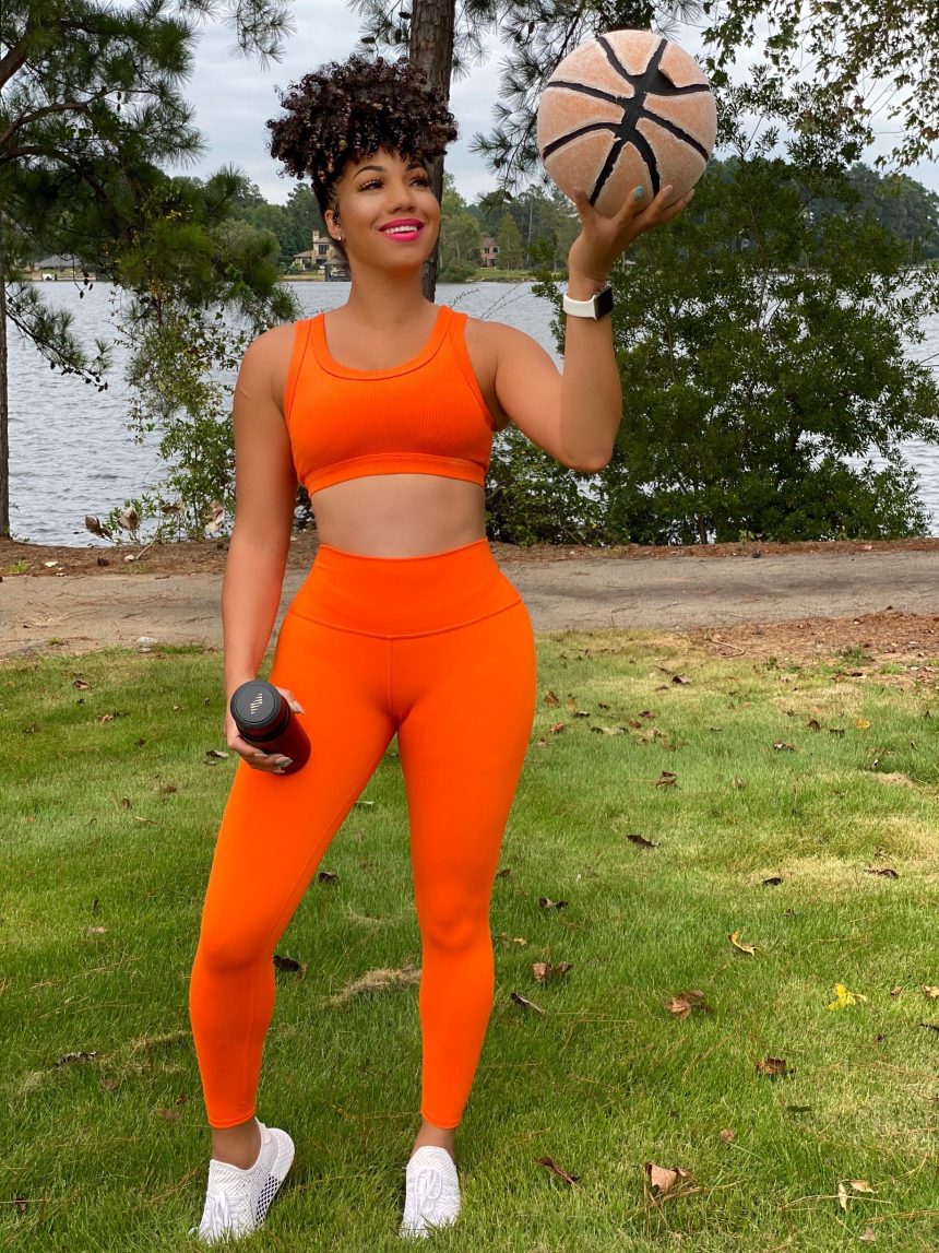 dr eva holding a basketball in orange workout clothes