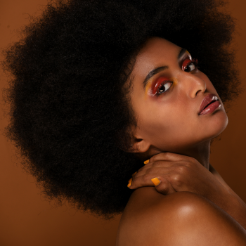 black curly afro hair on africal american woman posing in a brown background